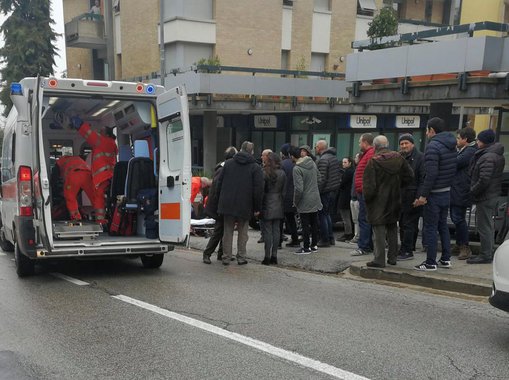 People look at healthcare personnel taking care of an injured person after being shot by gunfire from a vehicle, in Macerata, Italy, February 3, 2018. REUTERS/Stringer