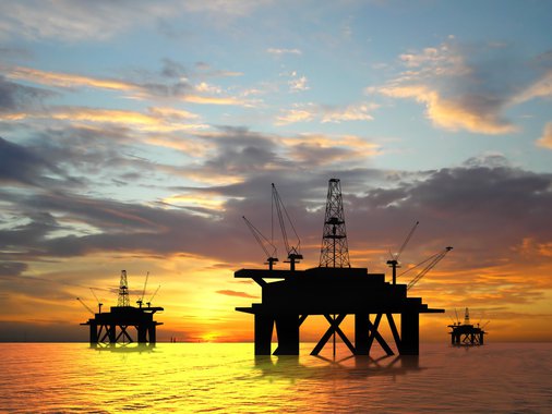 Oil rig silhouette over orange sky