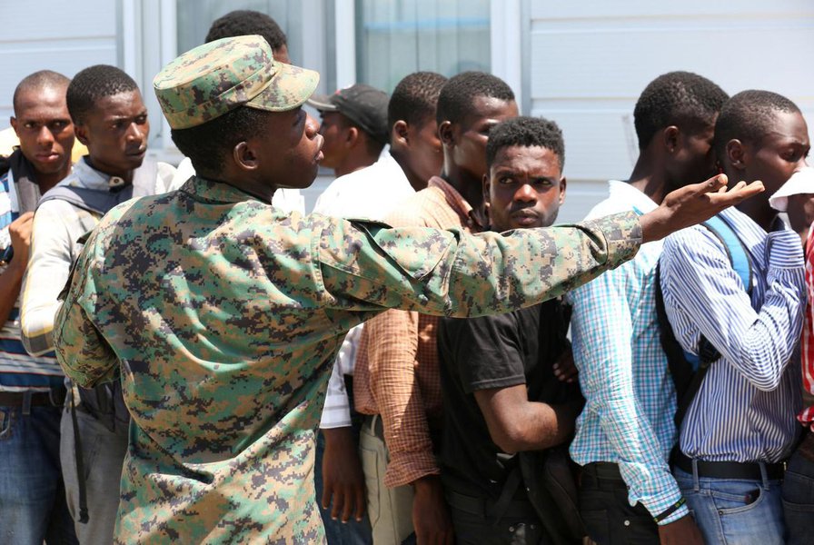 A soldier gestures as people stand in line seeking to join the country's reformed military in Gressier, Haiti July 18, 2017. REUTERS/Jeanty Junior Augustin