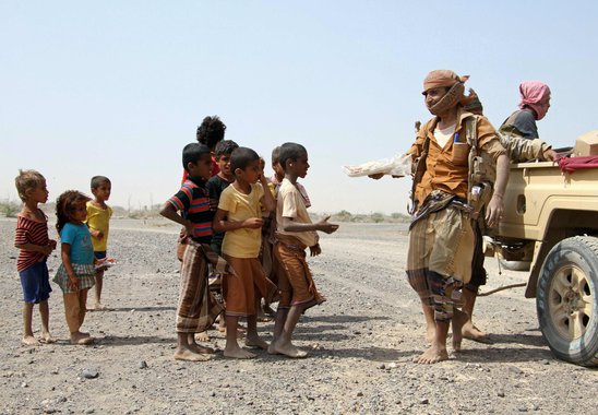 Pro-government fighters give food to Yemeni children on the road leading to the southwestern port city of Mokha on January 26, 2017. Yemeni rebels are putting up fierce resistance in a key Red Sea