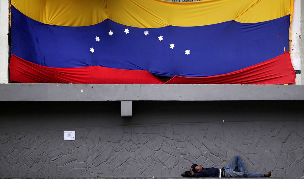 Homem deitado embaixo de bandeira da Venezuela em Caracas. 30/11/2016 REUTERS/Ueslei Marcelino