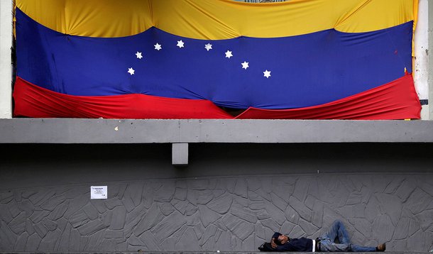 Homem deitado embaixo de bandeira da Venezuela em Caracas. 30/11/2016 REUTERS/Ueslei Marcelino