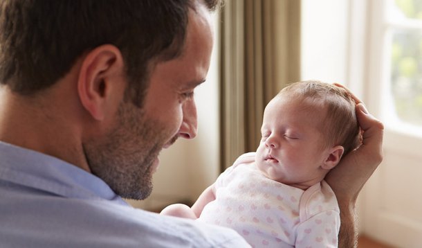 Father At Home With Sleeping Newborn Baby Daughter
