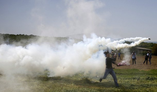 Imigrante arremessando lata de gás lacrimogêneo atirada pela polícia no vilarejo de Idomeni, na fronteira entre Grécia e Macedônia. 13/04/2016 REUTERS/Stoyan Nenov