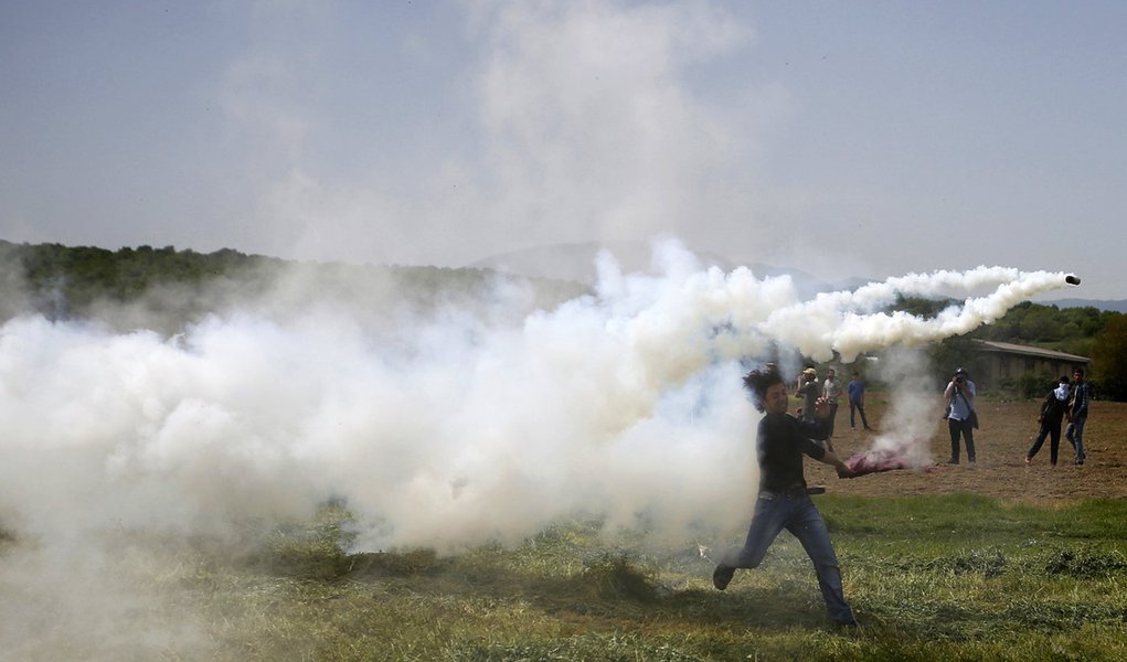 Imigrante arremessando lata de gás lacrimogêneo atirada pela polícia no vilarejo de Idomeni, na fronteira entre Grécia e Macedônia. 13/04/2016 REUTERS/Stoyan Nenov