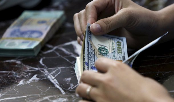 FuncionÃ¡rio conta notas de dÃ³lar norte-americano em banco de HanÃ³i, no VietnÃ£, nesta semana. 12/08/2015 REUTERS/Kham