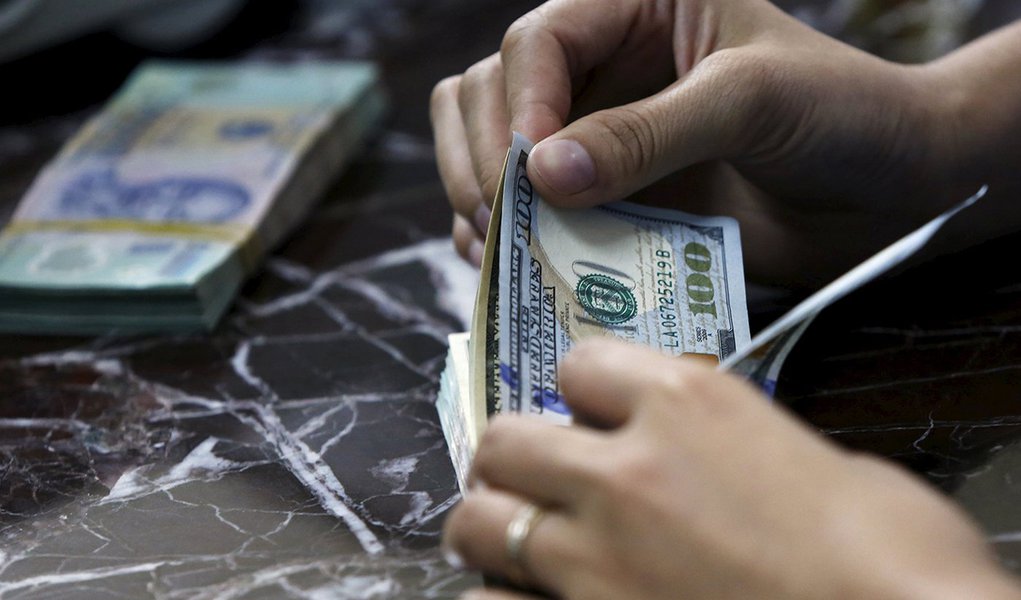 FuncionÃ¡rio conta notas de dÃ³lar norte-americano em banco de HanÃ³i, no VietnÃ£, nesta semana. 12/08/2015 REUTERS/Kham