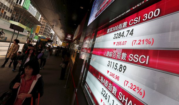 Pessoas passam por painel exibindo cotações de ações de bolsa na China, em Hong Kong. 07/01/2016 REUTERS/Bobby Yip