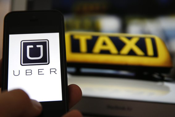 File illustration picture showing the logo of car-sharing service app Uber on a smartphone next to the picture of an official German taxi sign in Frankfurt, September 15, 2014. A Frankfurt court earlier this month instituted a temporary injunction against