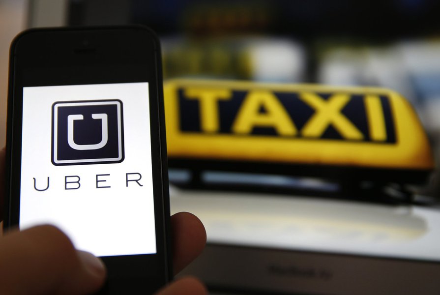 File illustration picture showing the logo of car-sharing service app Uber on a smartphone next to the picture of an official German taxi sign in Frankfurt, September 15, 2014. A Frankfurt court earlier this month instituted a temporary injunction against