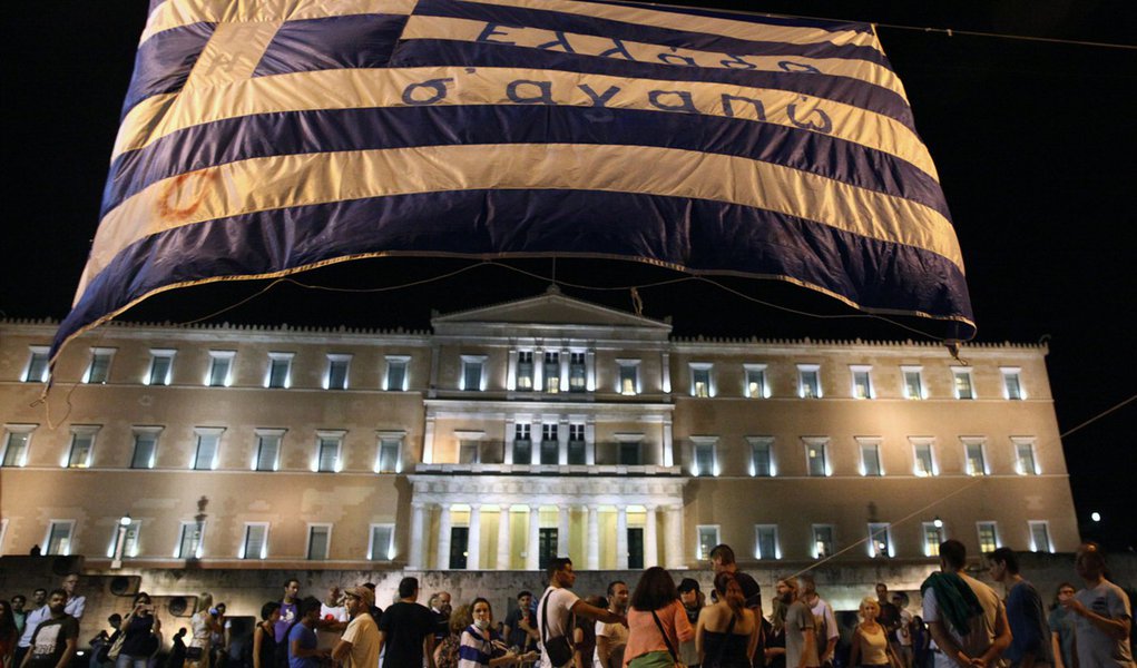 Manifestantes antiausteridade levantam uma bandeira da GrÃ©cia em frente ao Parlamento em Atenas. 15/07/2015 REUTERS/Yiannis Kourtoglou