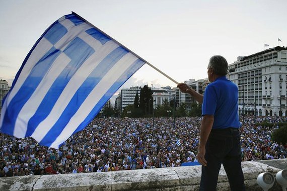 A protester waves a Greek flag at the entrance of the Greek parliament, during a rally calling on the government to clinch a deal with its international creditors and secure Greece's future in the Eurozone, in Athens June 18, 2015. Hopes of a breakthrough