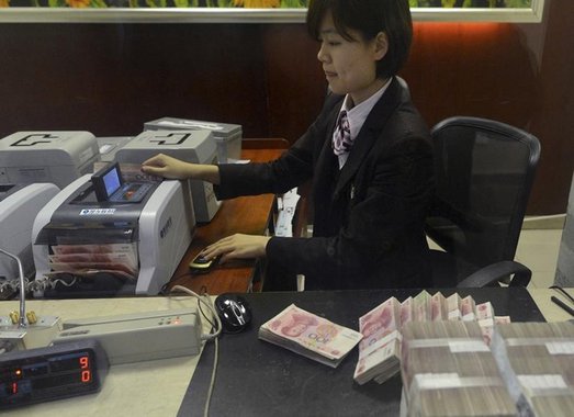 Funcionária conta notas de 100 iuanes em agência bancária na China. 20/04/2015 REUTERS/Stringer