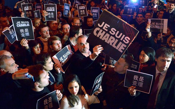 People holding banners reading "Je Suis Charlie" (I am Charlie) take part in an event in Beijing on January 8, 2015, in tribute to the twelve people killed the day before in an attack by two armed gunmen on the offices of French satirical newspaper Charli
