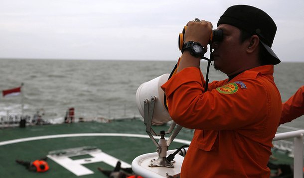 Agente da equipe de resgate da IndonÃ©sia usa binÃ³culo para tentar encontrar objetos suspeitos no mar de Java, na IndonÃ©sia, nesta sexta-feira. 02/01/2015 REUTERS/Beawiharta