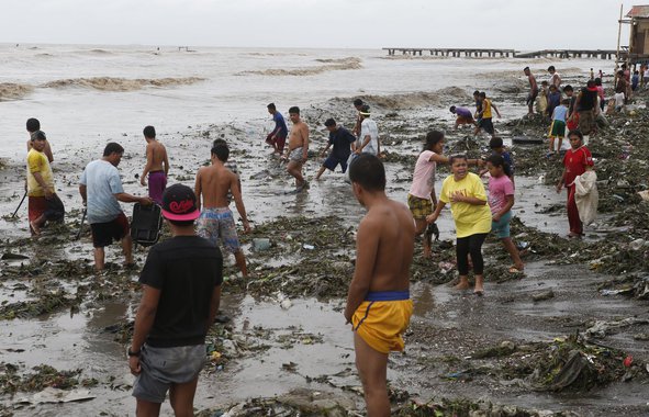 Moradores à beira-mar após a passagem do tufão Rammasun, no litoral da cidade de Rosário, ao sul de Manila. 16/06/2014.  REUTERS/Erik De Castro