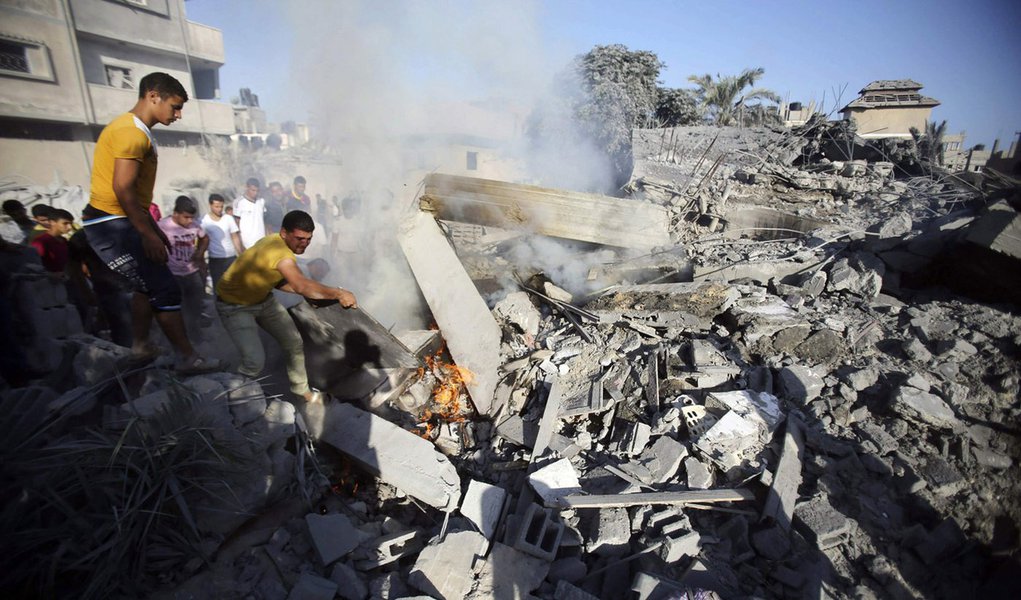 Palestinos tentam apagar fogo de destroÃ§os de casa atacada por Israel, segundo testemunhas, na Faixa de Gaza. 20/08/2014  REUTERS/Ibraheem Abu Mustafa