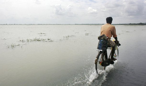 A man cycles along the flooded Karaitivu road in Kalmunai in Sri Lanka's east coast in this January 2, 2005 file photo. On December 26, 2004, a magnitude 9.15 quake off the coast of Indonesia's Aceh province triggered an Indian Ocean tsunami that killed a