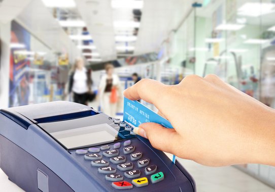 Human hand holding plastic card in payment machine in shop