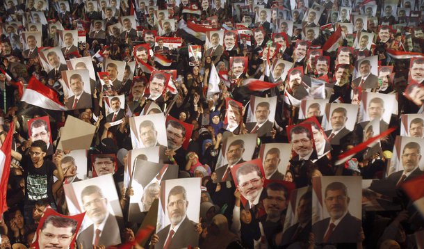 Members of the Muslim Brotherhood and supporters of Egypt's President Mohamed Mursi hold pictures of him as they react after the Egyptian army's statement was read out on state TV, at the Raba El-Adwyia mosque square in Cairo July 3, 2013. Egypt's armed f