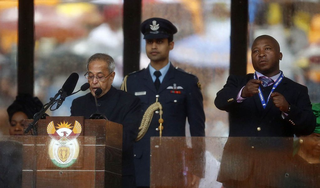 India's President Pranab Mukherjee speaks at the podium as a sign language interpreter (R) punches the air beside him during a memorial service for late South African President Nelson Mandela at the FNB soccer stadium in Johannesburg December 10, 2013. Th