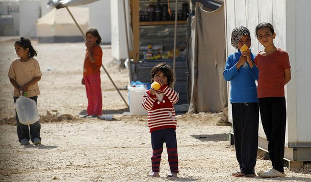 Young Syrian refugees look at the convoy of Japanese Foreign Minister Fumio Kishida and U.N. High Commissioner for Refugees (UNHCR) Antonio Guterres during their visit of Al Zaatri refugee camp in the Jordanian city of Mafraq, near the border with Syria, 
