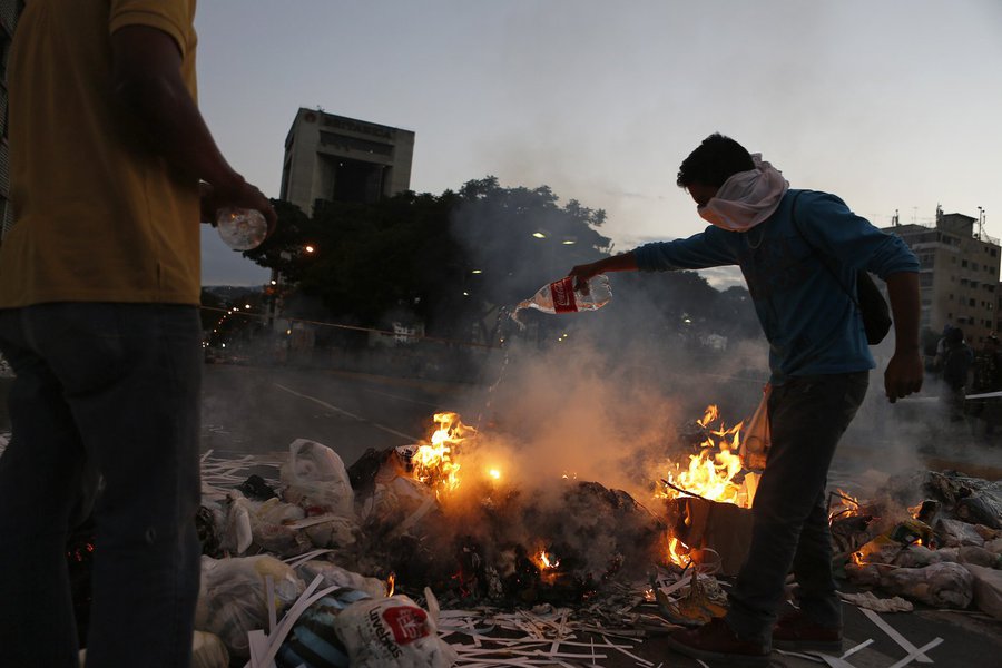 Opposition supporters stand near a burning barricade at Altamira square in Caracas February 20, 2014. Venezuelan security forces and demonstrators faced off in streets blocked by burning barricades in several provincial cities on Thursday as protests esca