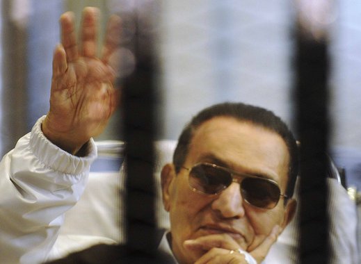 Former Egyptian President Hosni Mubarak waves to his supporters inside a cage in a courtroom at the police academy in Cairo April 13, 2013. The retrial of former Egyptian President Hosni Mubarak was aborted on Saturday when the presiding judge withdrew fr