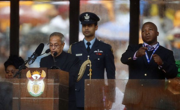 India's President Pranab Mukherjee speaks at the podium as a sign language interpreter (R) punches the air beside him during a memorial service for late South African President Nelson Mandela at the FNB soccer stadium in Johannesburg December 10, 2013. Th