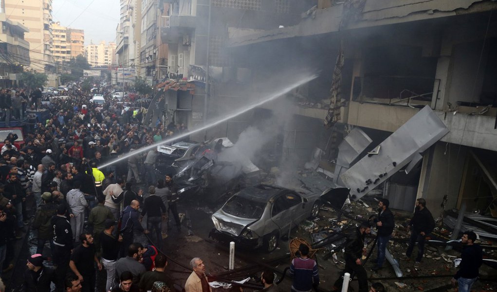 People gather as firefighters attempt to extinguish a fire at the site of an explosion in Beirut's southern suburbs, January 2, 2014. A car bomb killed four people in Hezbollah's southern Beirut stronghold on Thursday, security and medical sources said, t