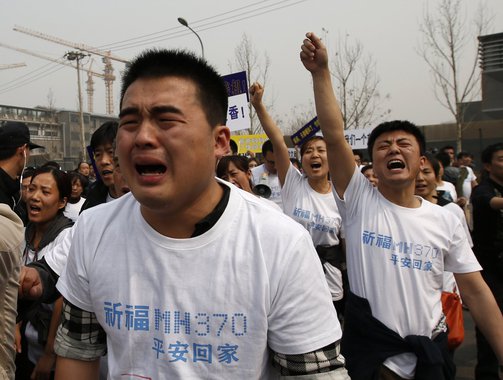 Family members of passengers onboard Malaysia Airlines MH370 cry as they shout slogans during a protest in front of the Malaysian embassy in Beijing March 25, 2014. Dozens of angry relatives of passengers on the lost Malaysian jetliner clashed with police