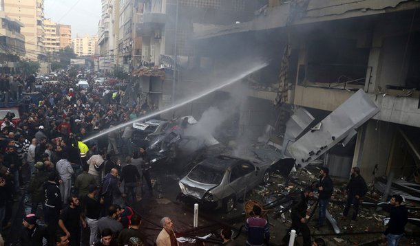 People gather as firefighters attempt to extinguish a fire at the site of an explosion in Beirut's southern suburbs, January 2, 2014. A car bomb killed four people in Hezbollah's southern Beirut stronghold on Thursday, security and medical sources said, t