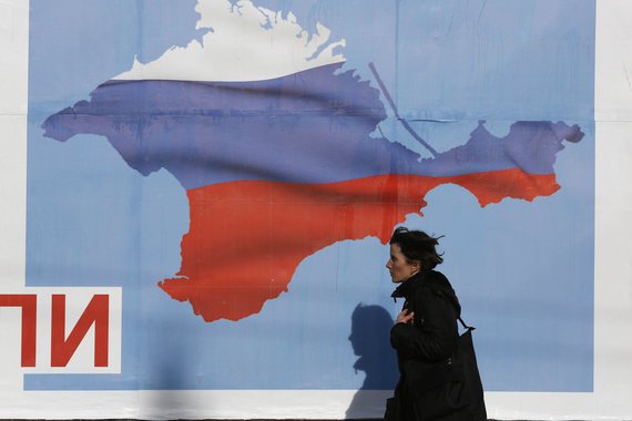 A woman walks by a poster in the Crimean port city of Sevastopol March 10, 2014. Crimea's parliament, dominated by ethnic Russians, voted to join Russia last week and set a referendum for March 16, escalating the crisis. REUTERS/Baz Ratner (UKRAINE - Tags