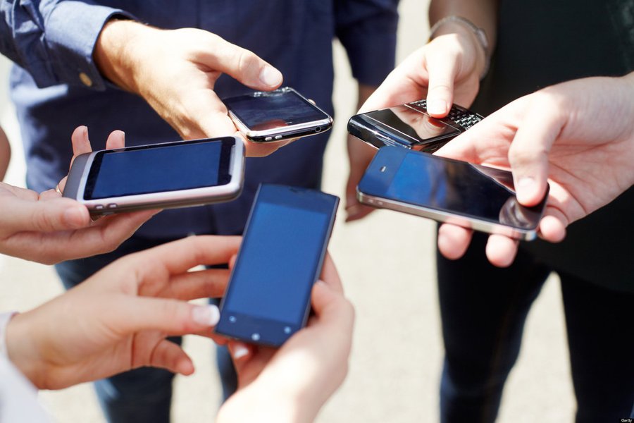 Close up of friends with circle of smart phones.