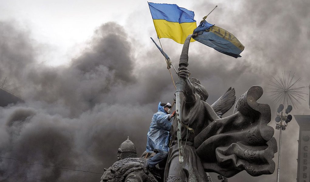 An anti-government protester sits on the Founders of Kiev monument during clashes with riot police in central Kiev on February 20, 2014. At least 25 protesters were killed on February 20 in fresh clashes between thousands of demonstrators and heavily-arme