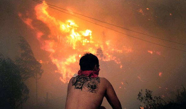 A local stares at houses in flames during a fire in Valparaiso, 110 km west of Santiago, Chile, on April 12, 2014. Authorities decreed a red alert for the area after the fire consumed more than 100 houses.   AFP PHOTO / FELIPE GAMBOA