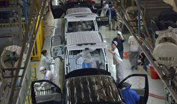 Employees work inside a factory manufacturing automobiles in Shenyang, Liaoning province, November 9, 2013. China's capital, Beijing, infamous for its thick smog and heavy traffic, will slash the city's new car sales quotas by almost 40 percent next year,