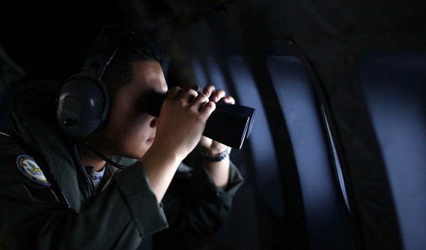 A crew member from the Royal Malaysian Air Force uses binoculars onboard a Malaysian Air Force CN235 aircraft during a Search and Rescue (SAR) operation to find the missing Malaysia Airlines flight MH370, in the Straits of Malacca March 13, 2014. REUTERS/