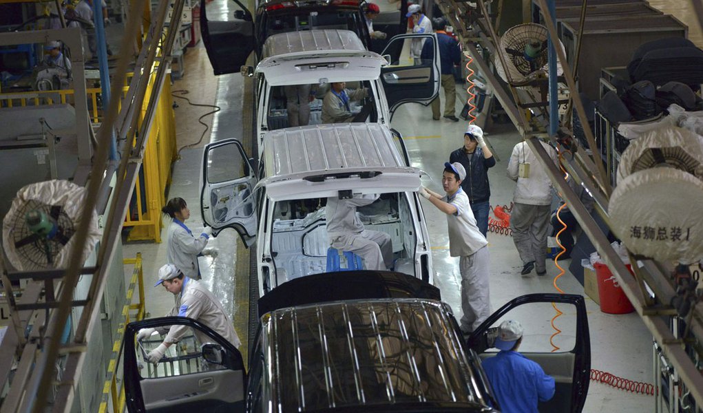 Employees work inside a factory manufacturing automobiles in Shenyang, Liaoning province, November 9, 2013. China's capital, Beijing, infamous for its thick smog and heavy traffic, will slash the city's new car sales quotas by almost 40 percent next year,