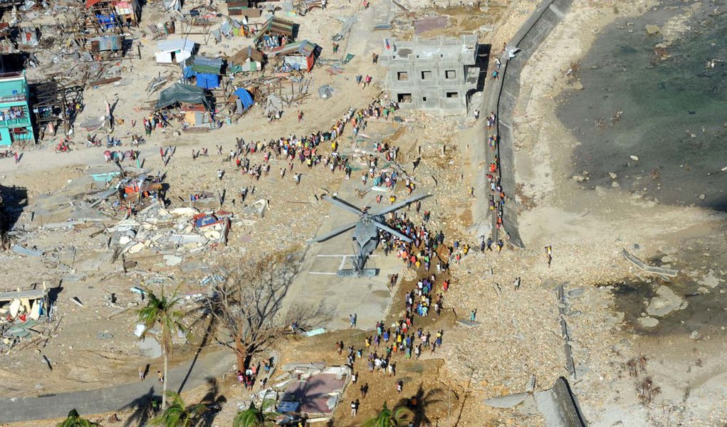 GUIUAN, Eastern Samar Province, Republic of the Philippines (Nov. 17, 2013) Philippine citizens gather around an MH-60S Sea Hawk helicopter from the Golden Falcons of Helicopter Sea Combat Squadron (HSC) 12 as it delivers relief supplies in support of Ope