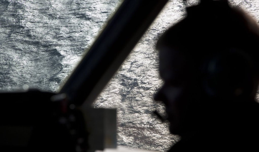 Captain Peter Moore is silhouetted against the southern Indian Ocean aboard a Royal Australian Air Force AP-3C Orion aircraft searching for missing Malaysian Airlines flight MH370, March 27, 2014. Severe weather on Thursday halted the air search for a Mal