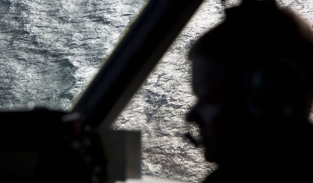 Captain Peter Moore is silhouetted against the southern Indian Ocean aboard a Royal Australian Air Force AP-3C Orion aircraft searching for missing Malaysian Airlines flight MH370, March 27, 2014. Severe weather on Thursday halted the air search for a Mal