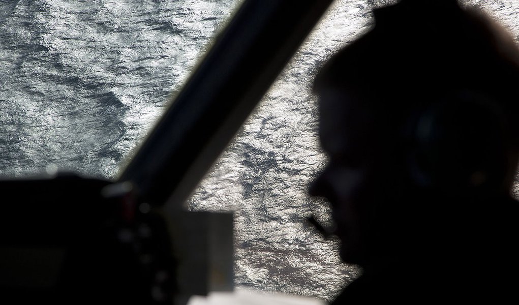Captain Peter Moore is silhouetted against the southern Indian Ocean aboard a Royal Australian Air Force AP-3C Orion aircraft searching for missing Malaysian Airlines flight MH370, March 27, 2014. Severe weather on Thursday halted the air search for a Mal
