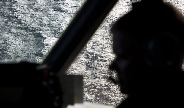 Captain Peter Moore is silhouetted against the southern Indian Ocean aboard a Royal Australian Air Force AP-3C Orion aircraft searching for missing Malaysian Airlines flight MH370, March 27, 2014. Severe weather on Thursday halted the air search for a Mal