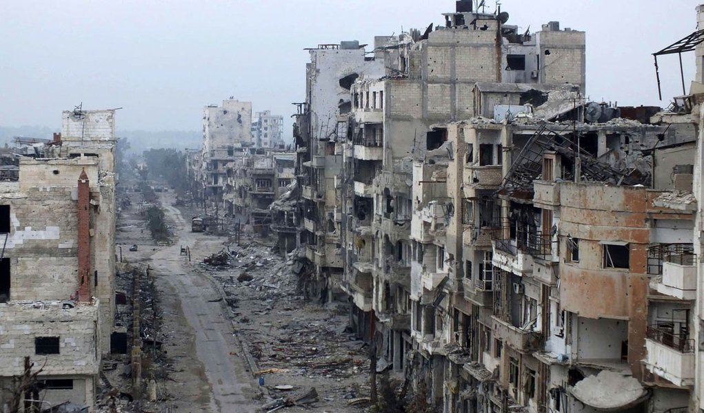 Damaged buildings line a street in the besieged area of Homs January 27, 2014. The United States on Monday demanded that Syria allow aid into the "starving" city of Homs, as talks aimed at ending three years of civil war hit more trouble over the future o