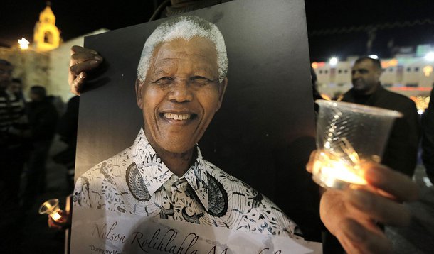 Palestinians light candles and hold placards bearing images of former South African President Nelson Mandela outside the Church of Nativity in the West Bank town of Bethlehem December 7, 2013. South African anti-apartheid hero Mandela died peacefully at h