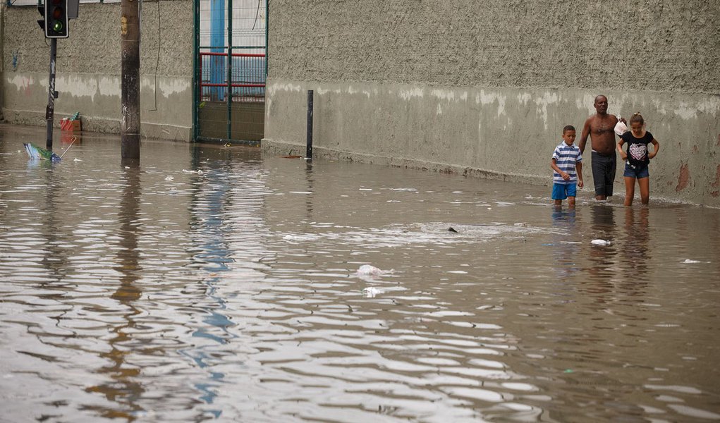 RIO DE JANEIRO, RJ - 11.12.2013: CHUVA/ESTRAGOS/RJ - Moradores passam por ponto de alagamento causado pela chuva na aveinda dos Democráticos, em Manguinhos, na zona norte da capital fluminense, na tarde desta quarta-feira. (Foto: Daniel Marenco/Folhapress