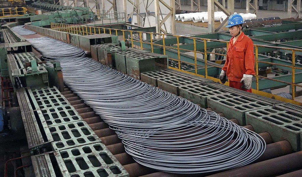 A labourer looks at steel coils next to a production line of Dongbei Special Steel Group Co., Ltd., in Dalian, Liaoning province September 27, 2013. Profits earned by Chinese industrial firms rose 24.2 percent in August from a year earlier to 483.2 billio