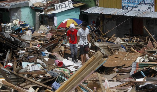 Residents walk past houses devastated by Typhoon Haiyan in Tacloban city, central Philippines November 13, 2013. Desperation gripped Philippine islands devastated by Typhoon Haiyan as looting turned deadly on Wednesday and survivors panicked over delays i