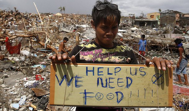 A typhoon victim holds a placard asking for food while standing amongst the ruins of houses destroyed by super typhoon Haiyan in Tanauan, Leyte in central Philippines November 14, 2013. Philippine President Benigno Aquino was under growing pressure on Thu